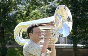 Musiker spielt im Freien ein großes glänzendes Blechblasinstrument