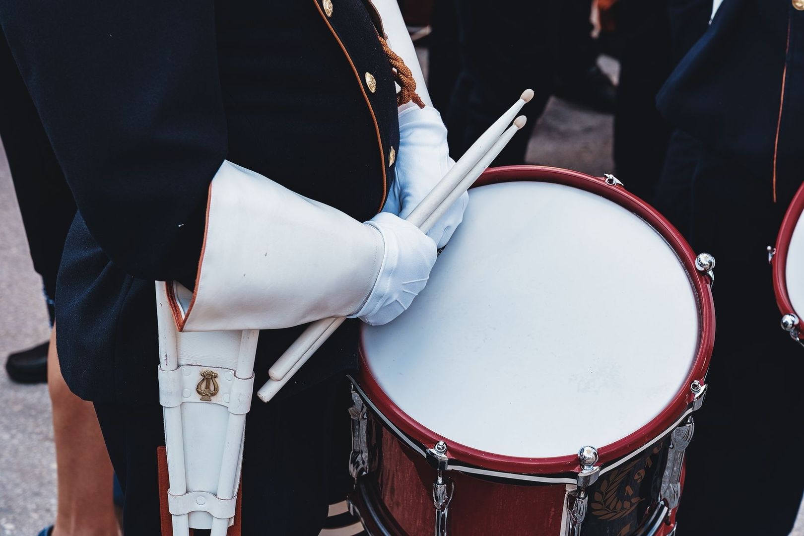 Marschmusiker mit weißen Handschuhen und Trommelstöcken an einer Snare-Drum