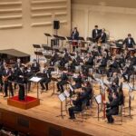 Dirigent leitet ein großes Blas- und Sinfonieorchester im Konzertsaal